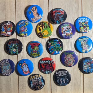 May include: A collection of 17 round, colorful button pins featuring various band logos and names, including "Attack! Attack!", "Motionless in White", "Bring Me The Horizon", "The Devil Wears Prada", "As I Lay Dying", "All Time Low", "Sleeping With Sirens", "A Day To Remember", "Suicide Silence", "We Came As Romans", "Alesana", "The Used", "Slivertstein", "Asking Alexandria", "Whitechapel", "Pierce The Veil", and "Fireflight".