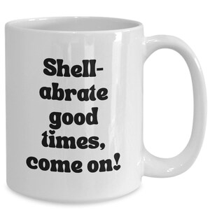 May include: White ceramic coffee mug with black text that reads "Shell-abrate good times, come on!"