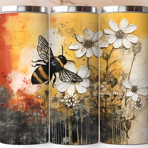 May include: A stainless steel tumbler with a bee and white flowers on a yellow and orange background. The bee is flying towards the flowers. The flowers are in a stylized, abstract style.