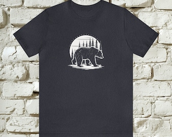 Può includere: Una t-shirt grigio scuro melange con una grafica bianca di un orso che cammina in una foresta davanti a una luna piena.