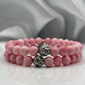 May include: Two pink gemstone bracelets with silver flower-shaped bead accents.