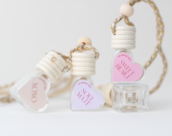 May include: Three heart-shaped car air fresheners with wooden tops and string hangers. The scents are "Soul Mate", "Sweet Heart", and "lolo".