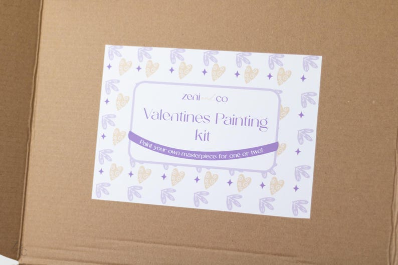May include: A white box with a purple and yellow design. The box says "Zeni & Co Valentines Painting Kit" and "Paint your own masterpiece for one or two!"