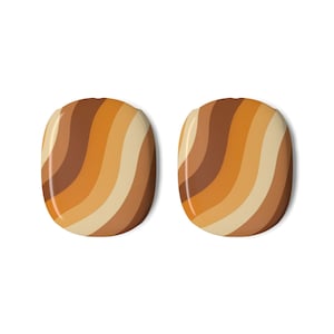 May include: A pair of oval-shaped decorative elements featuring a smooth, glossy finish with a repeating pattern of diagonal, wavy stripes in various shades of brown, tan, orange, and cream, creating a warm, layered color gradient effect.