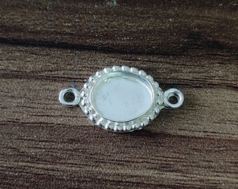 May include: Silver oval-shaped pendant with a beaded edge and two jump rings. The pendant is blank and ready for customization.