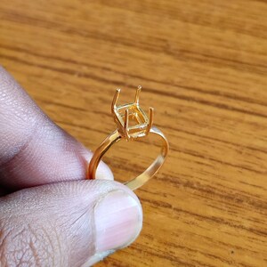 Op de afbeelding: Een gouden ring met een vierkante zetting voor een edelsteen. De zetting is open en klaar om met een steen te worden gevuld.