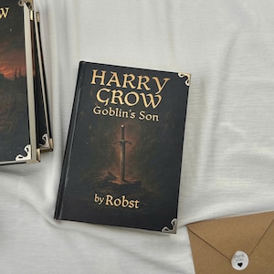 Pu&ograve; includere: Un libro nero intitolato "HARRY CROW Goblin's Son" con lettere dorate e un'illustrazione di spada. Il libro ha protezioni angolari argentate ed &egrave; di Robst. Diversi libri sono visibili, insieme a una busta marrone.