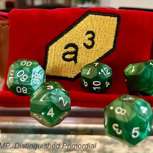 May include: A red velvet dice bag with a gold embroidered patch that says "a3".  The bag is open and there are eight green dice with white numbers on them.