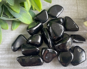 May include: A collection of black tumbled obsidian stones. The stones are smooth and polished, with a glossy finish.