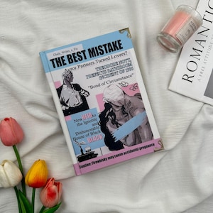 Puede incluir: Un libro titulado "THE BEST MISTAKE" con una portada azul claro e ilustraciones. La portada presenta texto que incluye "Auror Partners Turned Lovers?" y "Caution: Firewhisky may cause accidental pregnancy." Tambi&eacute;n se ven una vela rosa y una revista.
