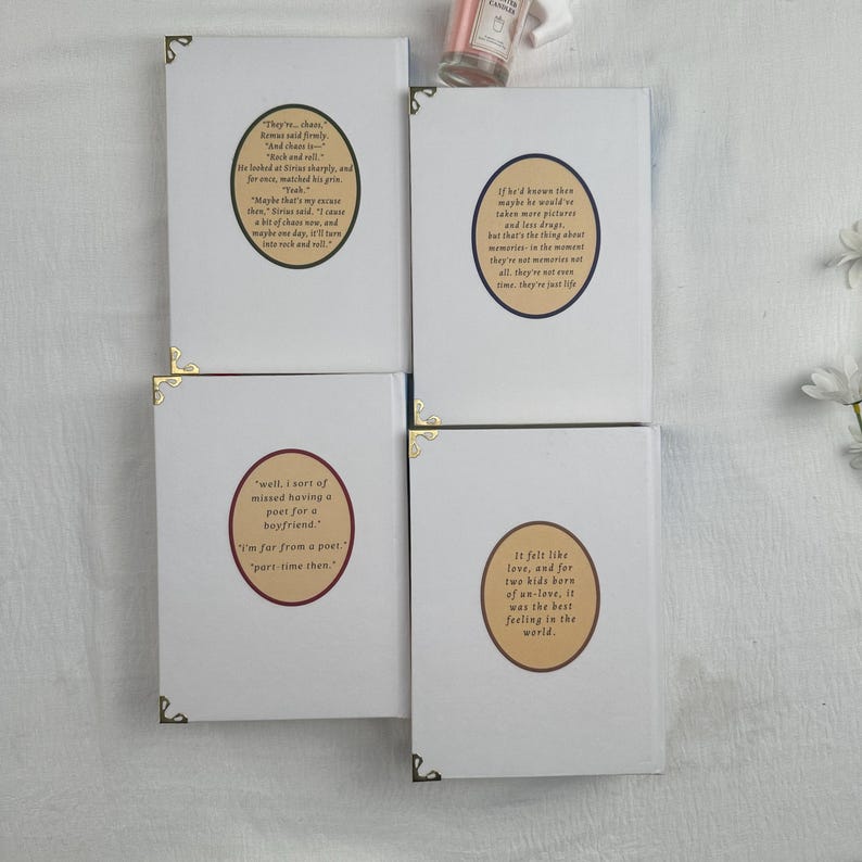 Pode incluir: Quatro cadernos brancos com cantos dourados. Cada caderno apresenta uma cita&ccedil;&atilde;o em um design circular. As cita&ccedil;&otilde;es est&atilde;o em fonte marrom. Os cadernos est&atilde;o dispostos em uma superf&iacute;cie branca.