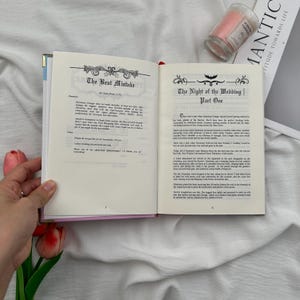 Puede incluir: Un libro abierto con texto en p&aacute;ginas color crema, con los t&iacute;tulos "The Best Mistake" y "The Night of the Wedding | Part One." Una vela rosa y una revista con la palabra "MANTIC" est&aacute;n en el fondo.