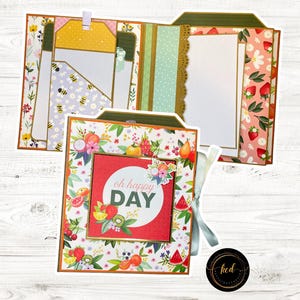 Könnte beinhalten: Ein handgefertigtes Scrapbook-Album mit Blumen- und Fruchtthema. Das Album zeigt ein rotes Quadrat mit den Worten "oh happy DAY" und ist von farbenfrohen Fruchtdarstellungen umgeben. Die Seiten haben verschiedene Muster und Farben.