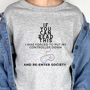 May include: A gray sweatshirt with the text "If you can read this I was forced to put my controller down and re-enter society" and a graphic of a video game controller.
