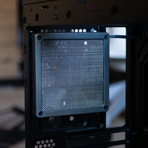 May include: A black computer case with a metal mesh panel on the side. The panel is designed to allow for airflow and cooling.