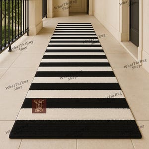 May include: A black and white striped runner rug. The rug has alternating thick black and off-white stripes. The rectangular rug is made of a textured material. The rug is placed on a tiled surface.