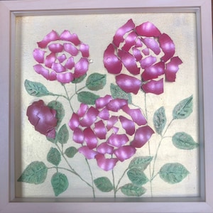 Può includere: Un'opera d'arte incorniciata con tre rose rosa realizzate con gusci d'uovo su uno sfondo dorato.