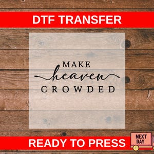 May include: A DTF transfer with the text "MAKE heaven CROWDED" in black script and block letters. The design is on a light background, set against a wooden plank backdrop. The words "READY TO PRESS" are at the bottom.
