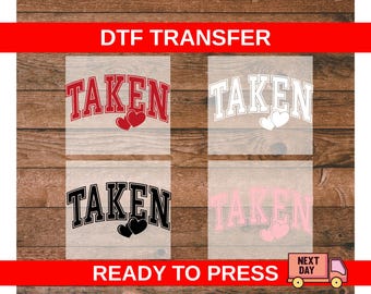 Puede incluir: Hojas de transferencia DTF con la palabra "TAKEN" en una fuente universitaria, combinada con gráficos de corazones. Disponibles en rojo, blanco, negro y rosa. También es visible el texto "READY TO PRESS".