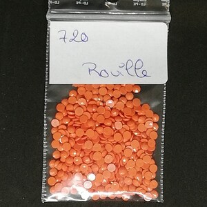 May include: A clear plastic bag filled with orange, round, diamond painting drills. A white label with the handwritten text "720 Rouille" is attached to the bag. The drills are a vibrant, solid color.