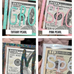 Puede incluir: Cuatro tarjeteros rectangulares con marcos y letras brillantes en acabados perlados Tiffany, rosa, negro y blanco. Cada soporte muestra una r&eacute;plica de un billete de 100 d&oacute;lares con el texto COPY MONEY MP. Las etiquetas dicen TIFFANY PEARL, PINK PEARL, BLACK PEARL y WHITE PEARL.