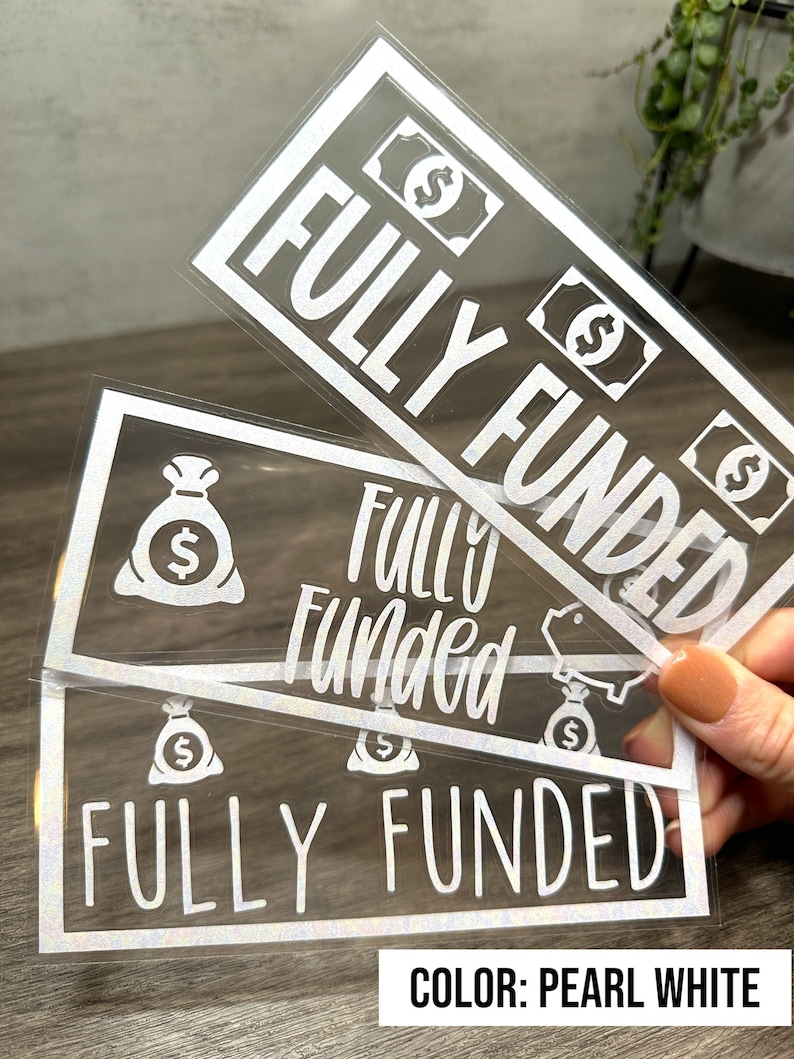Puede incluir: Tres calcoman&iacute;as rectangulares de vinilo blanco perla con el texto "FULLY FUNDED" en varias fuentes. Los dise&ntilde;os incluyen iconos de billetes, bolsas de dinero y una alcanc&iacute;a. Estos adhesivos tienen un acabado iridiscente sutil.