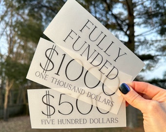 May include: Three translucent paper certificates with the text "Fully Funded" on the top certificate, "$1000 One Thousand Dollars" on the middle certificate, and "$500 Five Hundred Dollars" on the bottom certificate.