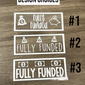 Puede incluir: Tres calcoman&iacute;as rectangulares de vinilo blanco etiquetadas #1, #2 y #3, cada una con el texto "FULLY FUNDED" en diferentes fuentes. El dise&ntilde;o #1 incluye un icono de bolsa de dinero y alcanc&iacute;a. El #2 tiene tres bolsas de dinero y el #3 tres billetes.