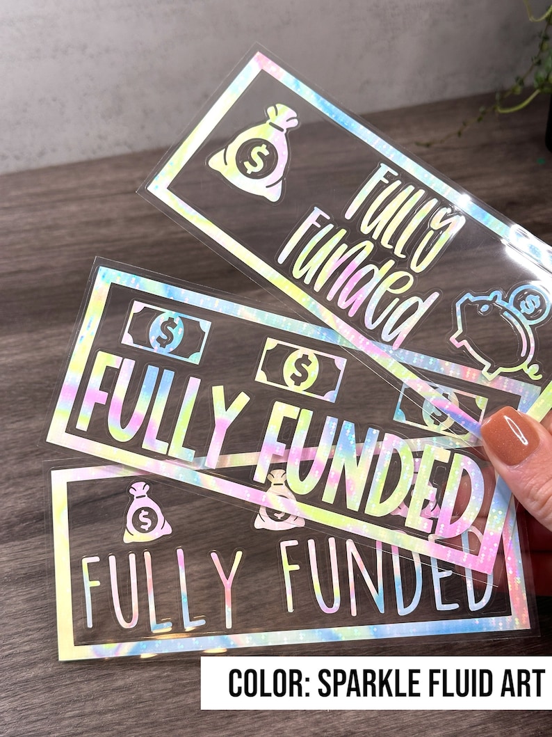 Puede incluir: Tres pegatinas rectangulares con un acabado hologr&aacute;fico de arte fluido brillante. Cada pegatina presenta el texto "FULLY FUNDED" en una fuente negrita, acompa&ntilde;ado de iconos gr&aacute;ficos de bolsas de dinero, billetes y una hucha.