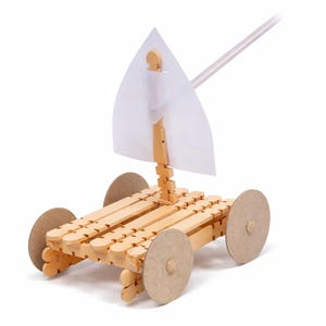 May include: A model sailboat made from wood, with a clear plastic sail and cardboard wheels. The body is constructed from wooden sticks. The mast supports a triangular sail. The wheels are circular and made of cardboard. The model is designed for educational purposes.
