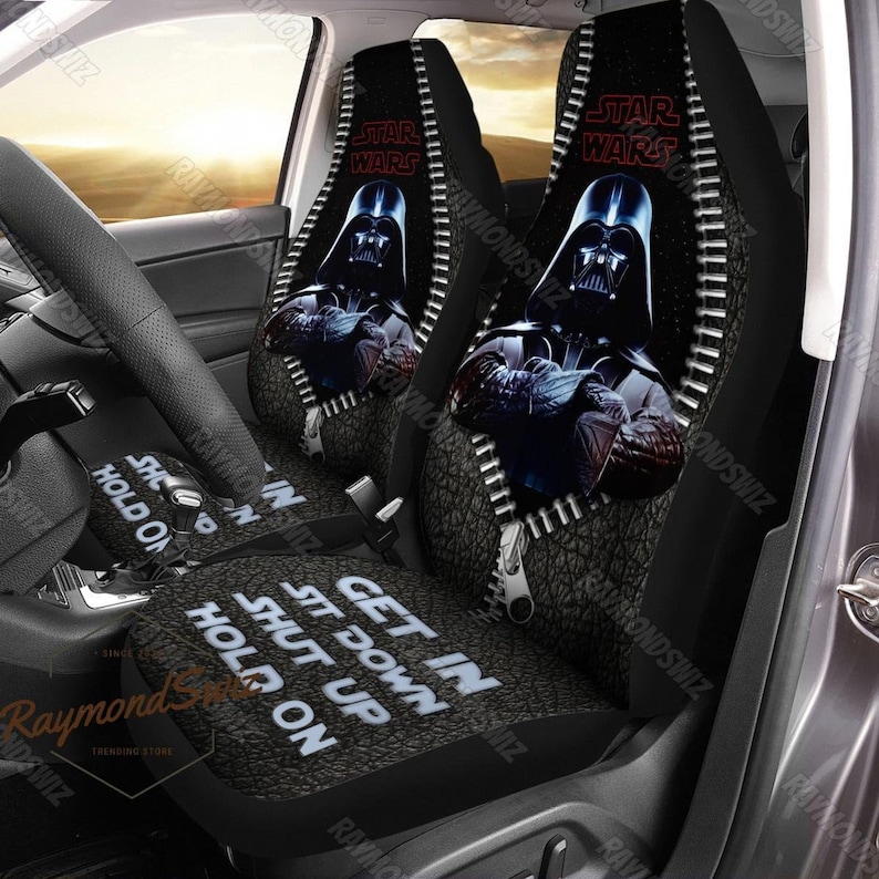 Puede incluir: Dos fundas para asientos de coche negras con un dise&ntilde;o de cremallera. Las fundas presentan un fondo gris oscuro con una imagen en blanco y negro de Darth Vader de Star Wars. El texto "Star Wars" est&aacute; impreso en rojo en las fundas. La parte inferior de las fundas tiene el texto "Get in, Sit Down, Shut Up, Hold On".