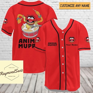 Könnte beinhalten: Rotes Baseballtrikot mit schwarzem Besatz. Die Vorderseite des Trikots trägt den Text "ANIMAL MUPPET" und ein Cartoon-Bild von Animal aus den Muppets. Die Rückseite des Trikots trägt den Text "ANIM MUPP" und ein größeres Bild von Animal, das Schlagzeug spielt. Der Text "Your Name" befindet sich auf der rechten Seite des Trikots.