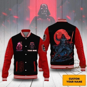 May include: A black and red baseball jacket with a Star Wars theme. The jacket features a Darth Vader graphic on the back and a smaller Darth Vader graphic on the front. The sleeves have the text "Darth Vader" on them. The jacket has a red and white striped collar and cuffs.
