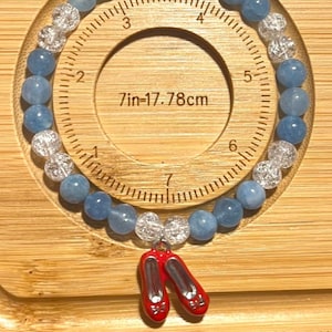 Kansas Girl Armband - Wicked & Wizard of Oz-inspirerat elastiskt armband med 6 mm glaspärlor och en rubinfärgad tofflorberlock