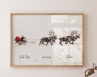 May include: A framed print of a watercolor illustration of Santa Claus in a red suit riding a sleigh pulled by reindeer. The text "Santa Claus is coming to town" is written below the image.