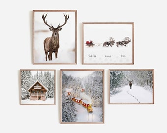 May include: Five framed winter-themed prints, including a red deer, a train in a snowy forest, a cabin in the woods, and two reindeer pulling a sleigh. The prints are all in brown frames and have a white background.