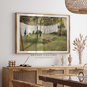 May include: A framed fine art print from ARTEVE GALLERY depicts a pastoral scene of white laundry hanging on a clothesline. The artwork is in a wooden frame and hangs above a wooden cabinet. The room is decorated with a woven light fixture and decorative vases.