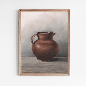 May include: A framed watercolor painting of a brown ceramic pitcher with a handle. The pitcher is centered on a wooden surface against a neutral background. The artwork is displayed in a light brown wooden frame.