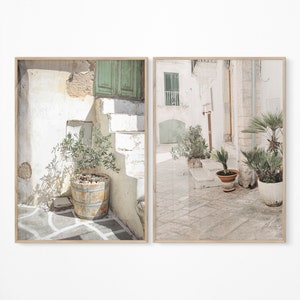 Peut inclure: Deux photographies encadrées d'une ruelle blanchies à la chaux dans une ville méditerranéenne. La photo de gauche montre un olivier en pot devant un bâtiment blanc avec une porte verte. La photo de droite montre une vue sur la ruelle avec des plantes en pot et un sol en pierre.