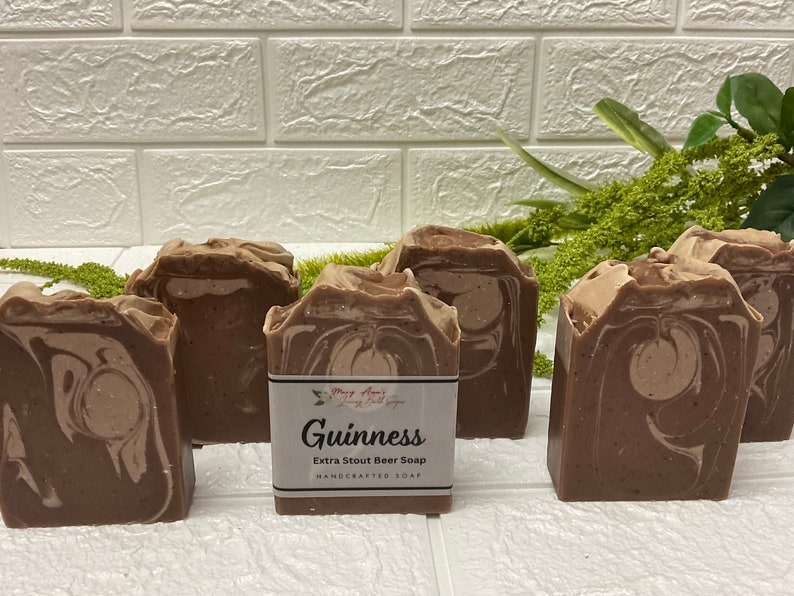 Op de afbeelding: Zes bruine en witte gemarmerde zeepjes met een label met de tekst "Guinness Extra Stout Beer Soap Handcrafted Soap".