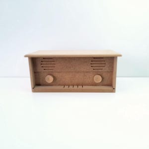 May include: A wooden radio with two knobs and a speaker grill. The radio is a light brown color and has a simple design.