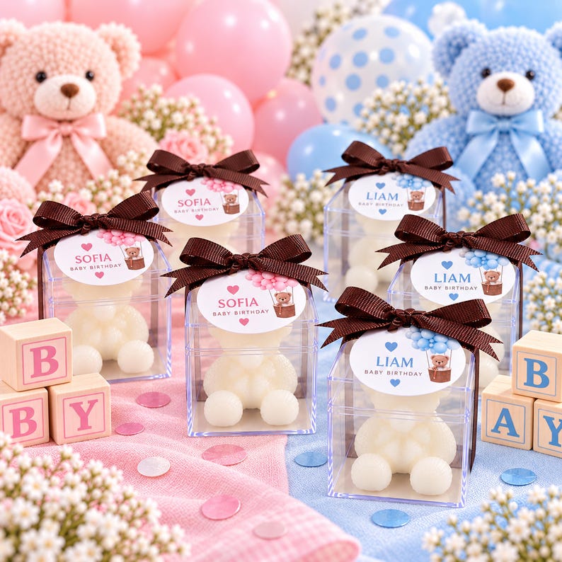 May include: Clear square boxes containing white teddy bear-shaped soaps, each topped with a brown ribbon and a personalized tag. Tags feature either the name Sofia with pink balloons or Liam with blue balloons and the text Baby Birthday.