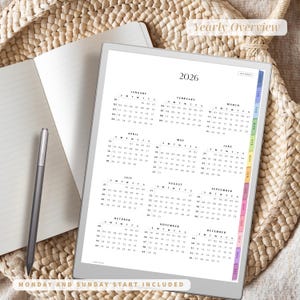 Puede incluir: Un planificador digital para el a&ntilde;o 2026, mostrado en una tableta. El planificador presenta una vista general anual con calendarios mensuales. Un cuaderno rayado y un l&aacute;piz &oacute;ptico est&aacute;n junto a la tableta. El texto "Yearly Overview" y "Monday and Sunday Start Included" son visibles.