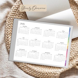 May include: A digital planner showing the year 2026, with a monthly calendar layout. The planner has colour-coded tabs and the words "Yearly Overview" at the top. The planner is on a woven surface.