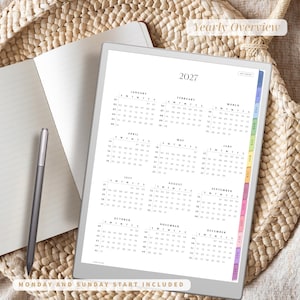 Puede incluir: Un planificador digital para 2027, con un calendario de vista general anual y dise&ntilde;os mensuales. El planificador incluye pesta&ntilde;as codificadas por colores y el texto "Yearly Overview" y "Monday and Sunday Start Included". Tambi&eacute;n se ven un bol&iacute;grafo y un cuaderno.