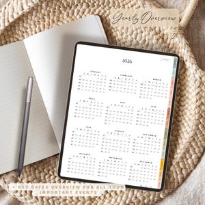 May include: A digital planner for 2026 displayed on a tablet, with a yearly overview calendar. The tablet is open to a page with the months of the year. A notebook and stylus are next to the tablet. Text on the image says "Yearly Overview" and "+ Key Dates Overview for All Your Important Events."