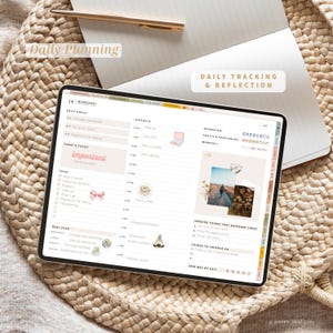 Pode incluir: Um planejador digital exibido em um tablet, com uma programa&ccedil;&atilde;o di&aacute;ria, lista de tarefas e prompts de reflex&atilde;o. O texto inclui "Daily Planning" e "Daily Tracking & Reflection". O tablet est&aacute; em uma superf&iacute;cie tecida, com uma caneta e um caderno ao fundo.