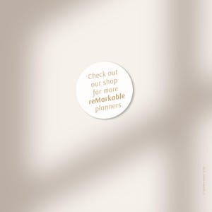 Puede incluir: Una pegatina circular blanca con el texto "Check out our shop for more reMarkable planners" en marr&oacute;n claro. El fondo es un degradado borroso de beige y marr&oacute;n claro.