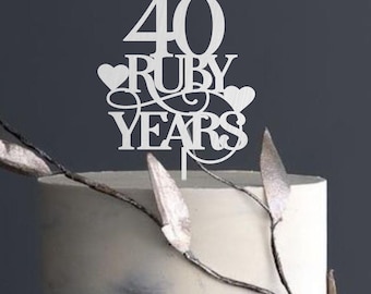 May include: White cake topper with the text "40 Ruby Years" and two hearts. The topper is on a white cake with a marble design.