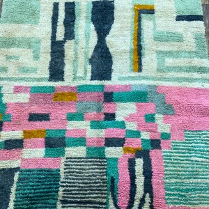 Op de afbeelding: Een kleurrijk tapijt met een geometrisch patroon in tinten roze, groen, blauw en geel. Het tapijt heeft een modern, abstract ontwerp.